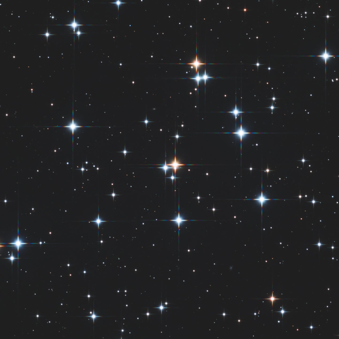 Star cluster with prominent, thin spikes. The spikes have a rainbow diffraction pattern.