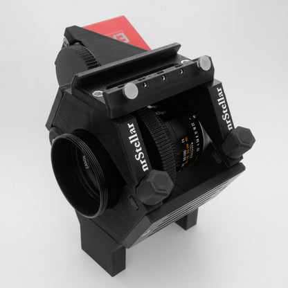 A nrStellar customized ring kit holding a lens. There is a finderscope shoe and a ZWO electronic autofocuser attachment.